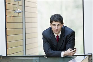 Mixed race businessman leaning on office railing
