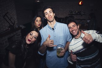 Laughing friends giving thumbs up in nightclub
