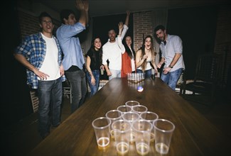 Friends playing beer pong at party