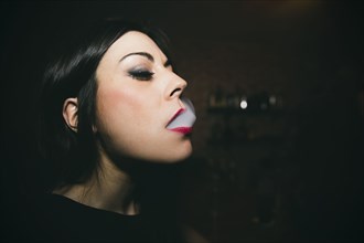 Caucasian woman smoking in nightclub