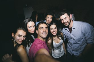 Smiling friends taking selfie in nightclub