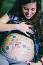 Pregnant Caucasian woman with drawings on belly