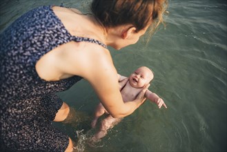 Caucasian mother holding baby daughter in ocean