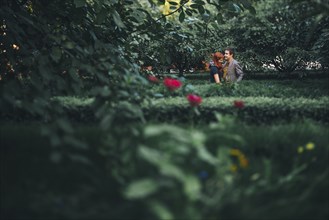Distant Caucasian couple standing behind hedges