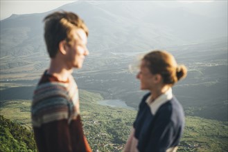 Caucasian couple standing on mountain over valley