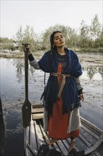Caucasian woman wearing traditional clothing in rowboat
