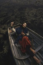 Location woman wearing traditional clothing laying in rowboat