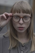 Portrait of serious Caucasian woman holding eyeglasses