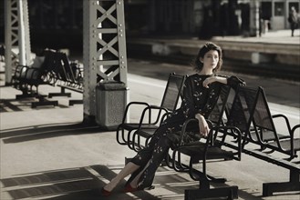 Caucasian woman sitting on bench at train station