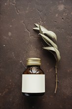 Alternative medicine jar with blank label near leaf