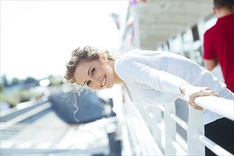 Smiling Caucasian woman leaning over railing