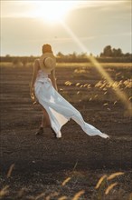 Sexy Caucasian woman wearing white dress walking in field