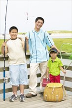 Portrait of father fishing with sons