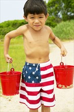 Boy carrying buckets at beach