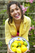 Portrait of woman holding bowl of lemons