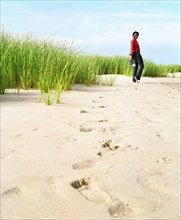 Young woman leaving footprints in sand