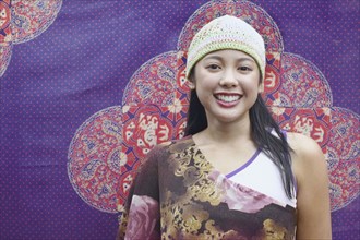 Asian woman smiling in front of tapestry