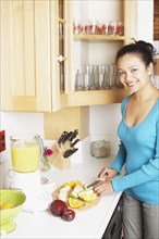 Young woman chopping fruit in the kitchen
