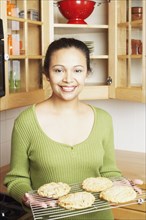 Young woman holding a rack of baked goods