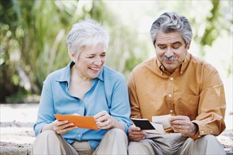 Middle-aged couple looking at photographs outdoors