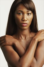 Nude African woman covering breasts
