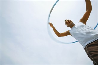 Hispanic man playing with plastic hoop