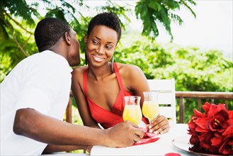 African couple drinking orange juice on patio