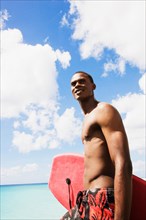 African man holding body board on beach