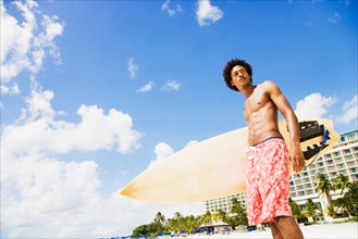 African man holding surfboard on beach