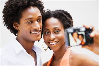 African couple taking self-portrait with digital camera