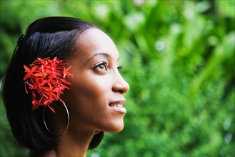 African woman with flowers in hair looking up