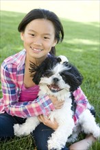 Chinese girl sitting in grass with Shih Tzu dog