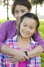 Chinese mother hugging daughter outdoors