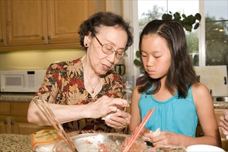Chinese grandmother cooking with granddaughter