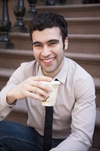 Hispanic businessman drinking coffee on front steps