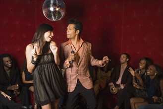 Man and woman singing karaoke at nightclub