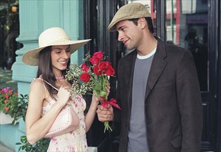 Hispanic man giving flowers to girlfriend