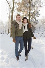 Caucasian couple pulling sled in snow