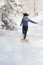 Caucasian woman pulling sled in snow
