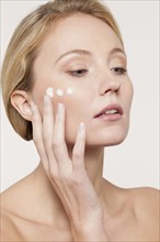 Nude Caucasian woman applying moisturizer