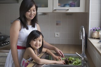 Asian mother and daughter washing vegetables
