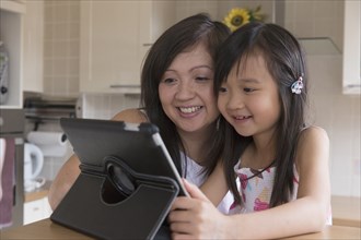 Asian mother and daughter using digital tablet