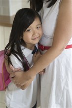 Asian mother and daughter hugging in kitchen