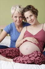 Caucasian pregnant lesbian couple relaxing on bed