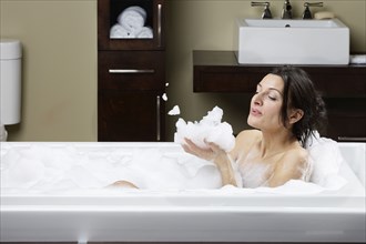Caucasian woman blowing bubbles in bubble bath