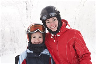 Caucasian mother and daughter smiling in snow