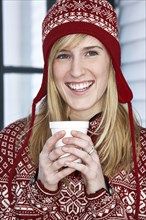 Caucasian woman in winter hat with cup of coffee