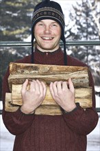 Caucasian man carrying firewood in snow