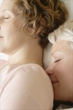 Caucasian lesbian couple sleeping on bed