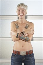 Caucasian woman with bare chest showing off tattoos